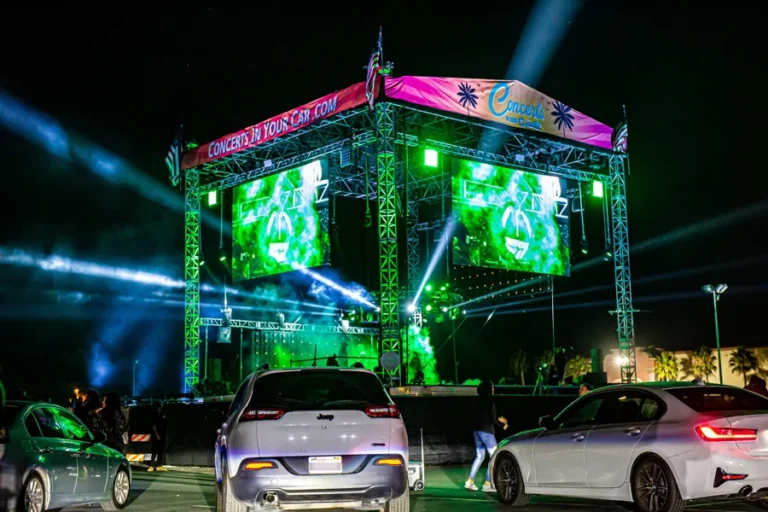 A full concert stage surrounded by the drive-in audience’s vehicles.