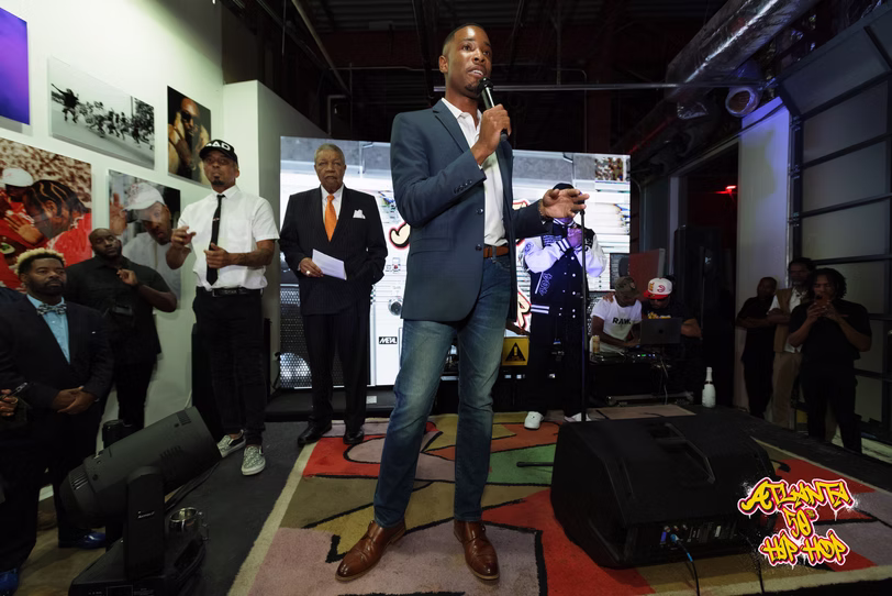 A speaker with a microphone addresses the opening-night audience.