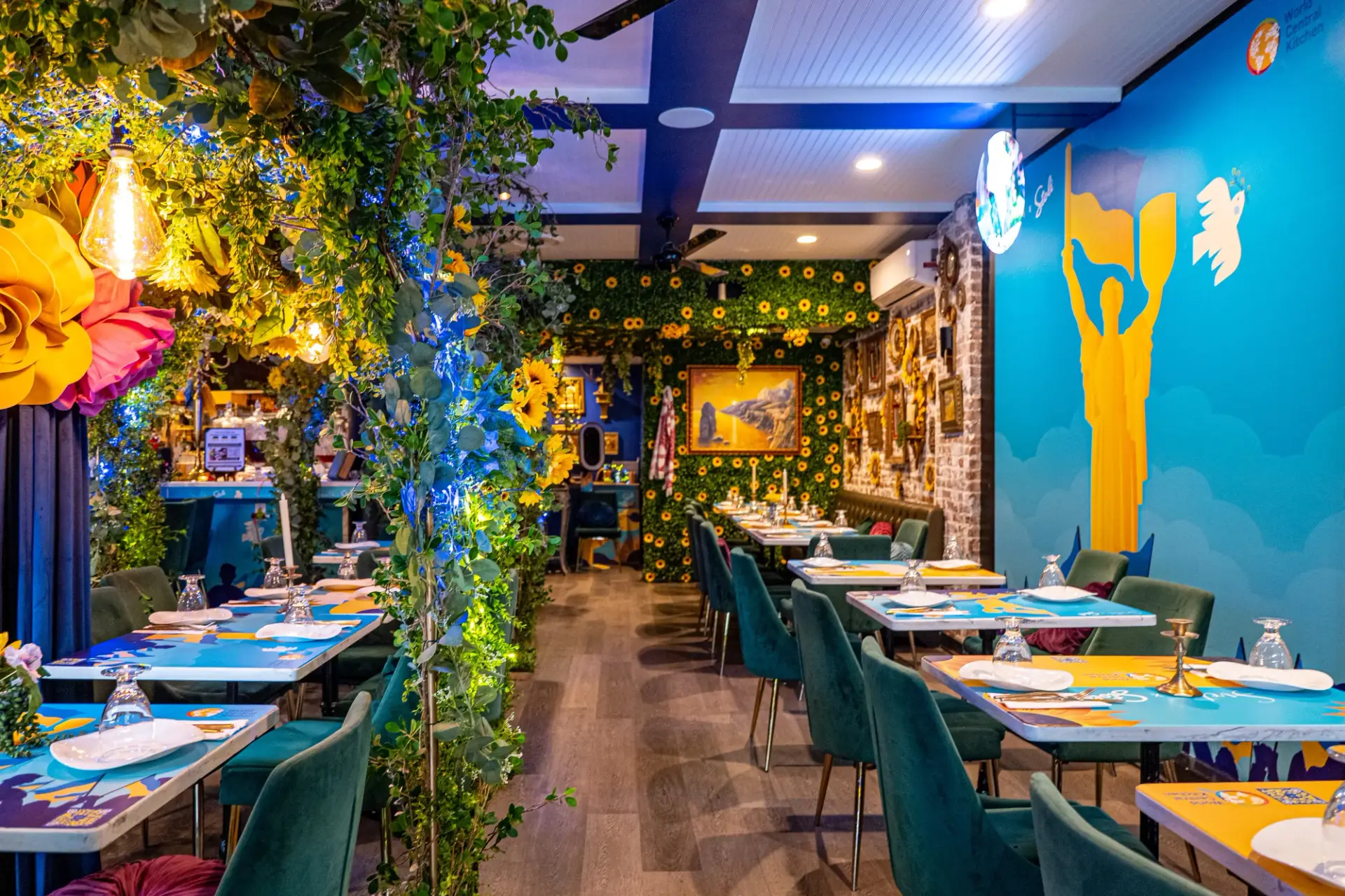 Inside Cocktails for Ukraine at Sveta: a restaurant transformed through florals, blue-and-yellow graphics and Ukrainian cultural references.