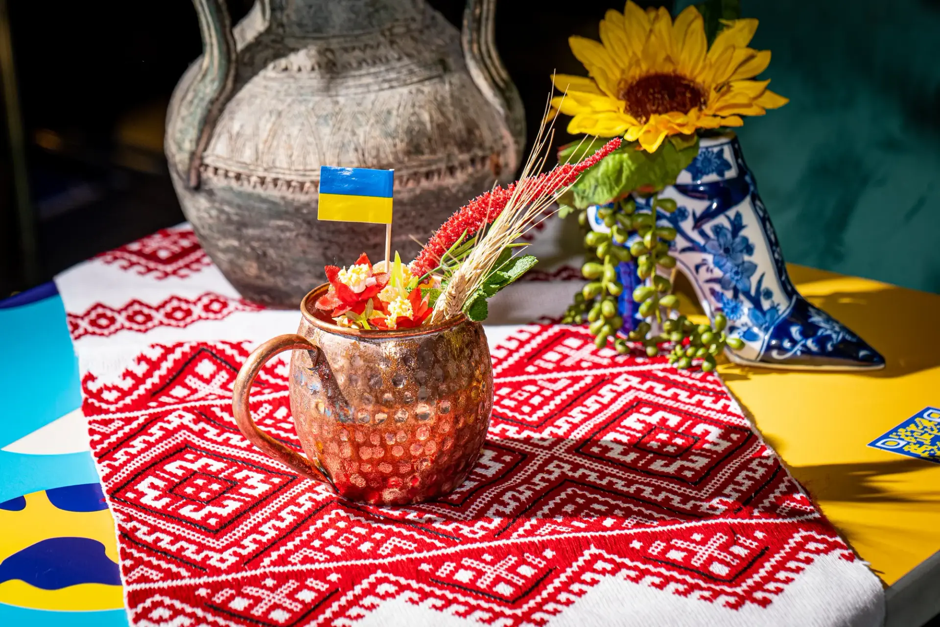 Cocktail presentation with Ukrainian flags and an embroidered table detail.